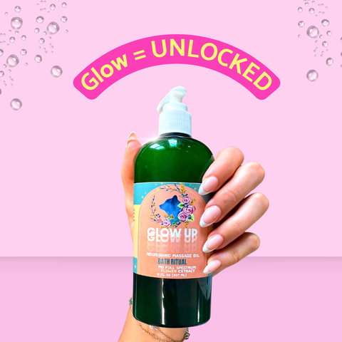Hand holding a bottle of 'Glow Up' bath ritual oil with a pink background and text 'Glow = Unlocked'.