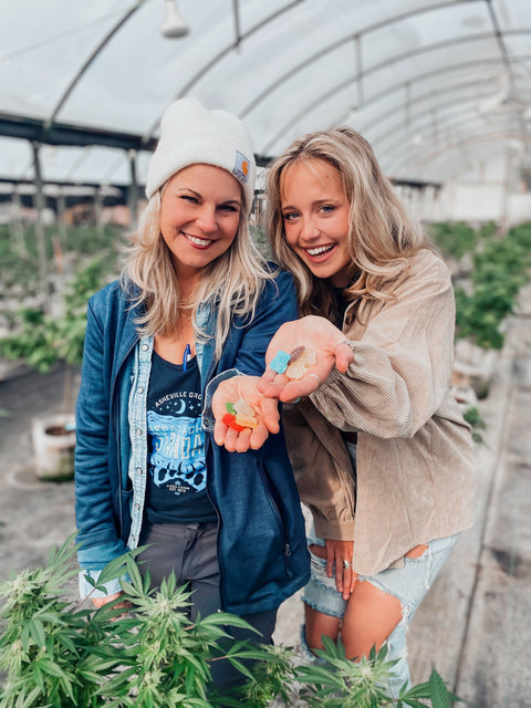 Lauren Davis, of Fiddy Shades of Green, and her mom stand smiling in a greenhouse while holding Boujee Bear CBD Gummies