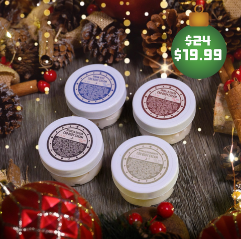 Four 1.5 oz size jars of Appalachian Standard's CBD body cream surrounded by holiday decorations, including pine cones, cinnamon sticks, and Christmas ornaments