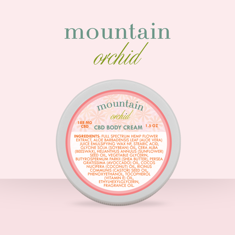 Appalachian Standard Mountain Orchid CBD Body Cream tin, 188mg, 1.5 oz, displayed on a soft pink background. The round tin features a blush and coral label with a daisy pattern.