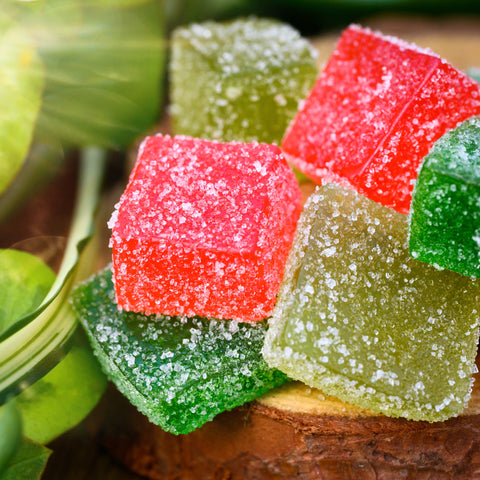 Six THC-Free Gummies coated with sugar piled on a wood slice
