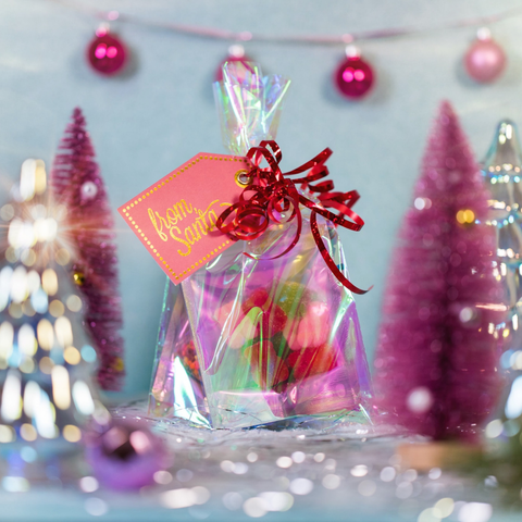 Gift bag with a 'From Santa' tag in front of Christmas trees and decorations