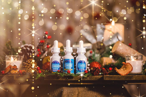 Three bottles of Appalachian Standard's tinctures surrounded by Christmas decorations