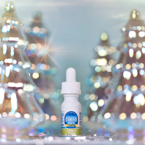 Bottle of candy cane-flavored vape juice with blurred Christmas trees in the background
