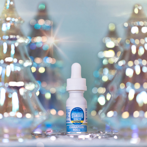 Bottle of cinnamon-flavored vape juice with blurred Christmas trees in the background